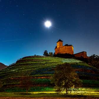 Burg Gutenberg bei Nacht unter Vollmond, eingebettet in die Weinberge
