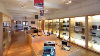 Blick in einen hellen Ausstellungsraum des Lawena Museums mit beleuchteten Vitrinen voller historischer Elektrogeräte.
