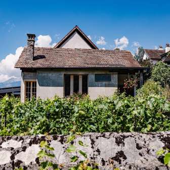 Traditionelles Haus des Restaurants Torkel, umgeben von Weinreben mit Blick auf die Alpen.