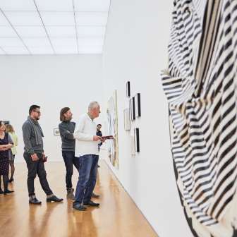Besuchergruppe im Ausstellungsraum des Kunstmuseums, im Vordergrund ein grosses, rundes Kunstwerk