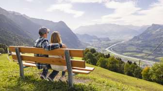 Two hikers sit on a bench and enjoy the view of the Rhine Valley