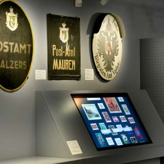 Museumsraum mit alten Postschildern und einem digitalen Display zur Geschichte der Post in Liechtenstein