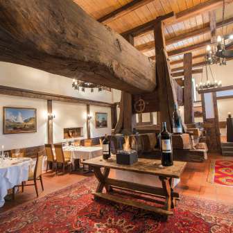 Rustic dining room with historic wooden beams, fireplace and set tables in the Torkel restaurant.