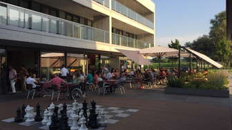 Well-frequented sun terrace of the Pizzeria Toscana with a large chess field