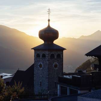 Zwiebelturm der Pfarrkirche St. Josef mit untergehender Sonne im Hintergrund