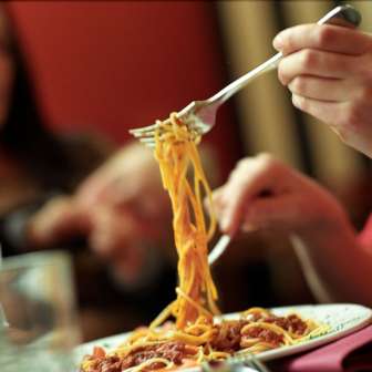 Person hebt mit der Gabel Spaghetti von einem Teller in der Brasserie Burg