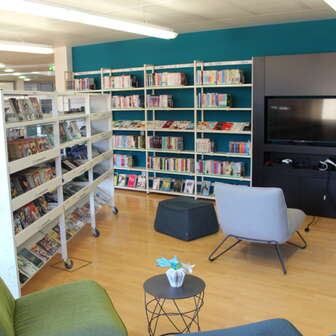 Gemütliche Leseecke in der Liechtensteinischen Landesbibliothek mit Sesseln und Medienwand zwischen hohen Bücherregalen