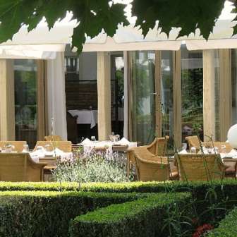Sunny garden terrace of the Vivid restaurant with set tables and a view of the countryside