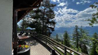 „Sonnenterrasse mit Panoramablick über das Rheintal bei klarer Sicht und gemütlicher Sitzgelegenheit im Alpenstil im Berggasthaus Matu