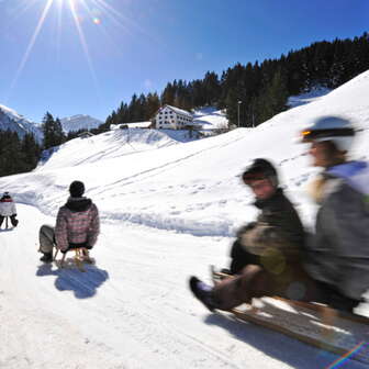 Lehrer Personen rodeln die Rodelstrecke an einem schönen sonnigen Tag in der Winterlandschaft