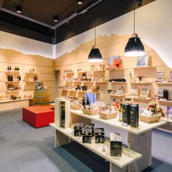 Helles Besucherzentrum mit modernen Holzregalen, gefüllt mit Souvenirs, Spezialitäten und Informationsmaterialien