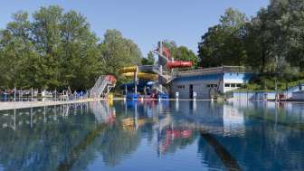 Blick auf das grosse Schwimmbecken mit bunter Rutschenlandschaft im Schwimmbad Mühleholz
