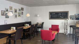 Cosy café with modern seating, decorative picture wall and warm wooden floor