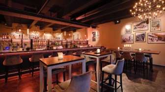 Elegant restaurant interior with dark wood features, bar area and comfortable chairs in a cozy setting.