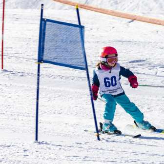 Little child with race number driving through the gates in the children's ski race in the malbi-park