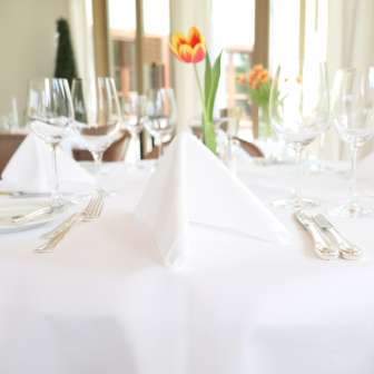 Festively set table with white tablecloth and fresh tulip