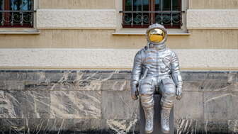 Silver astronaut sculpture "Space Conductor" by Max Grüter in front of the government building in Vaduz – modern art in public space.