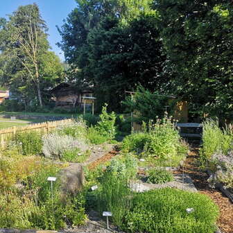 lick auf den Kräutergarten in Mauren mit beschrifteten Pflanzenbeeten, blühenden Kräutern und gepflegten Wegen in sommerlicher Umgebung.