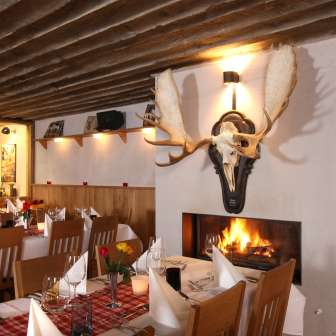 Gemütliches Restaurantambiente mit rustikalen Holzbalken und Kamin