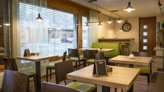 Modern bistro with a cosy ambience, wooden tables and stylish green benches