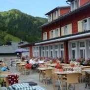Sunny terrace of the restaurant with set tables, parasols and views of the Alps.