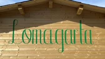 Ansicht auf das grüne Lömagarta-Logo, das stilvoll auf der Holzfassade des gemütlichen Biergartens prangt.