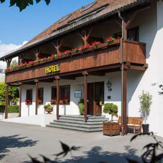 Exterior view of the Vivid restaurant with traditional façade, wooden balcony and blooming flower boxes