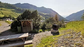 Grillplatz Schlucher-Treff mit Sitzbank, Feuerstelle und Blick ins Liechtensteiner Bergpanorama bei Sonnenschein