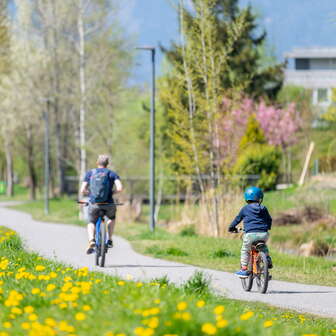 Familie radelt auf dem Frühlingsradweg im Naturpark Haberfeld, umgeben von blühenden Wiesen und Bäumen.