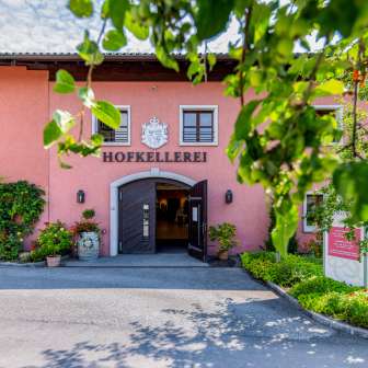 Eingangsbereich der Hofkellerei des Fürsten von Liechtenstein in Vaduz, umgeben von grünem Laub und Blumen.