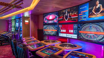 Moderne Spieltische mit digitalen Bildschirmen und mehreren Roulette- und Kartenspieloptionen im stimmungsvoll beleuchteten Casino Schaanwald.
